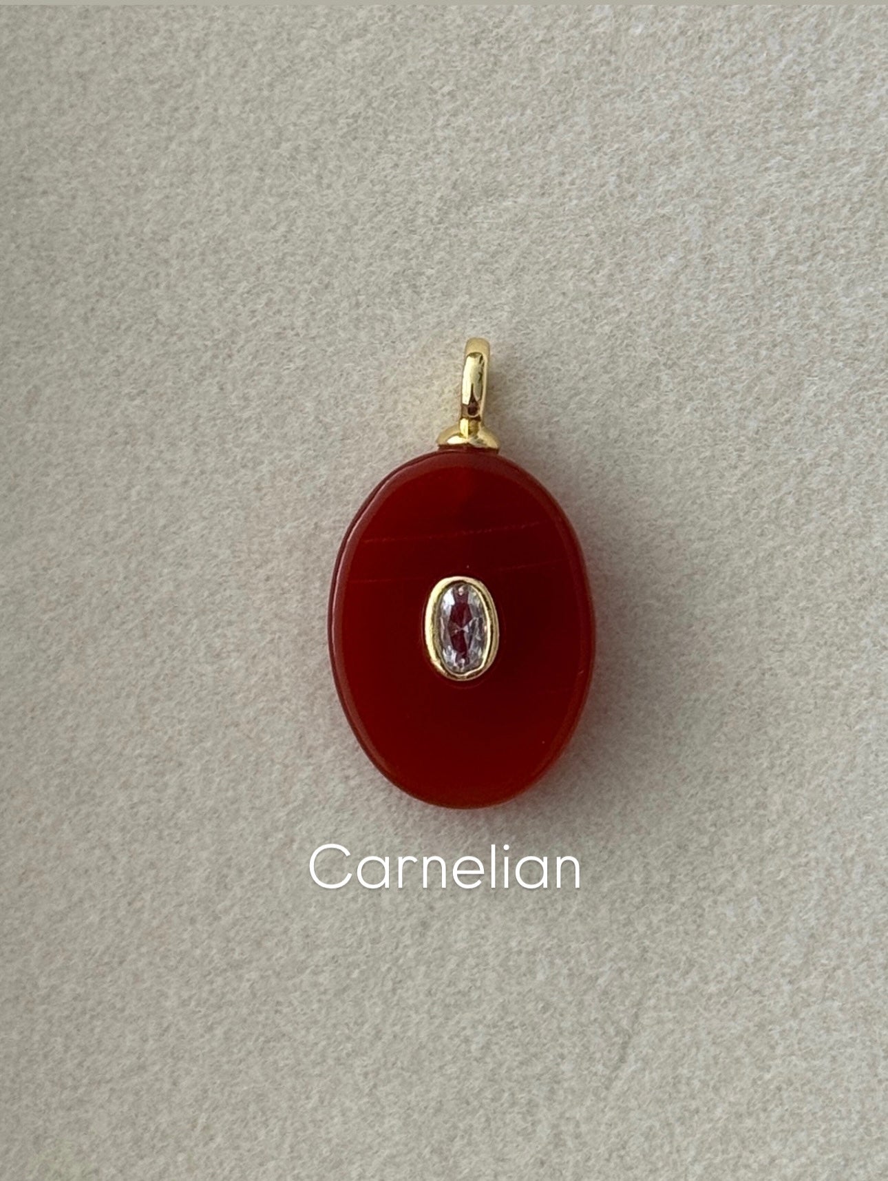 Carnelian pendant with gold and silver accents on a gray background