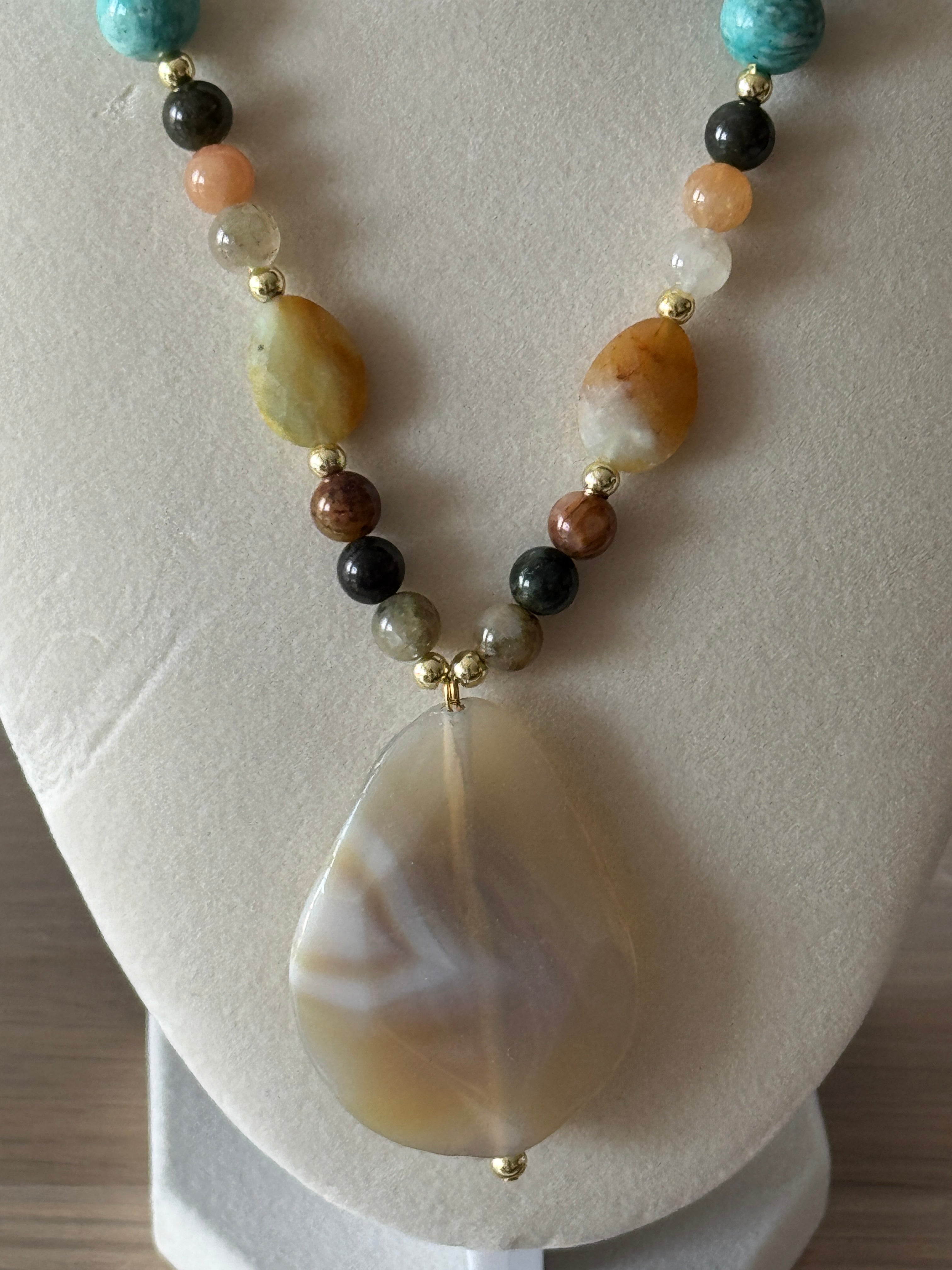Necklace with multicolored beads and a large shell pendant on a light background